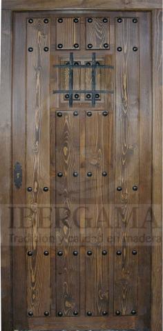 Puerta rústica exterior de tablas y ventanuco con reja.